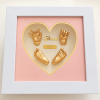 Mẫu tranh Baby Art được thiết kế với khung vuông trắng sang trọng, kích thước 30x30cm, nổi bật với mặt trái tim màu hồng nhẹ nhàng, tinh tế. Bên trong là dấu tay – dấu chân 3D của bé phủ vàng ánh kim, kết hợp cùng tên bé và thông tin ngày sinh, tạo nên tổng thể ấm áp, đáng yêu và đầy ý nghĩa. Sản phẩm phù hợp để lưu giữ kỷ niệm đầu đời của bé, trang trí không gian gia đình hoặc làm quà tặng đầy tháng, thôi nôi rất ý nghĩa